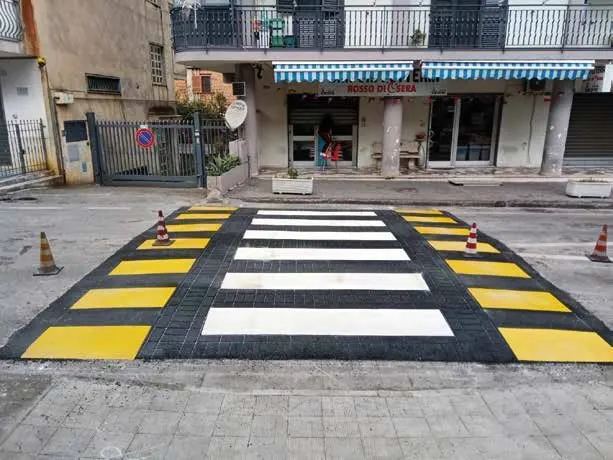 Attraversamento pedonale rialzato con fasce bianche e gialle in centro urbano